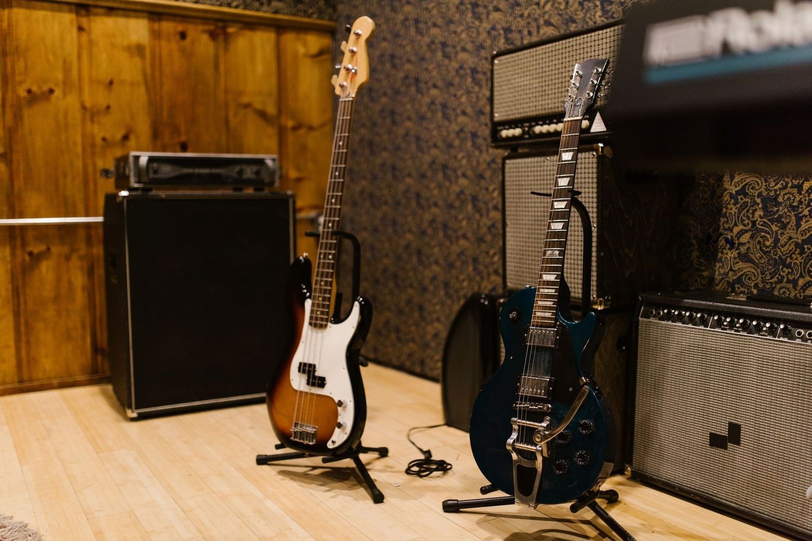 E-Gitarre, Bass und Verstärker in einem holzvertäfelten Musikstudio