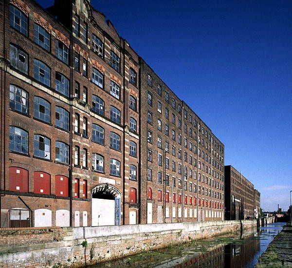 Historische Backsteinfabrik am Kanal unter tiefblauem Himmel in Manchester